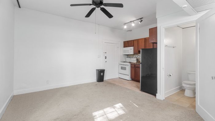 a white room with a ceiling fan and a refrigerator at The Suites of Irvington